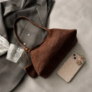 Vue détaillée de la texture en daim marron foncé et de la bandoulière du sac hobo