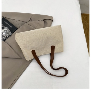Primo piano della borsa tote in tela beige con manici in pelle marrone su fondo in tessuto