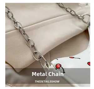 Détail de la chaîne en métal argenté et imprimé cerise sur sac bandoulière en cuir
