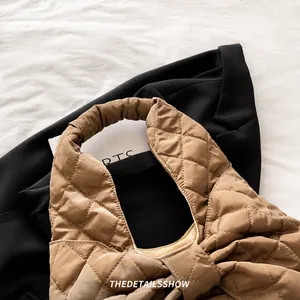 Detail of khaki quilted tote bag with soft pleated handle on black blazer suit