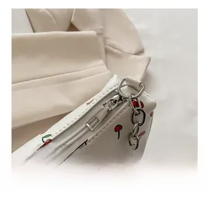 Détail de la fermeture éclair argentée et motif cerise sur le sac blanc élégant