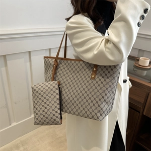 Macro detail of the beige geometric tote bag set with brown leather handles and small pouch