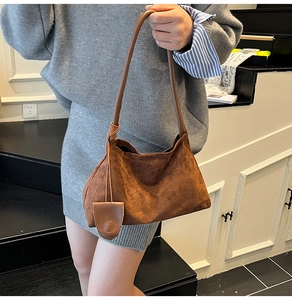 Détail du sac hobo en daim marron foncé avec bandoulière ronde en cuir et nœud décoratif