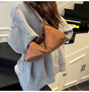 Sac sous le bras en daim marron avec bandoulière en cuir porté par un mannequin en intérieur