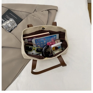 Vista dall'alto dell'interno della borsa in tela con tablet, taccuino e occhiali