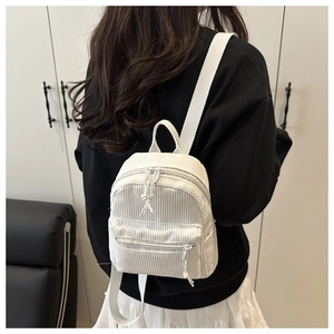 Detailed view of a white corduroy mini backpack with textured fabric on a model