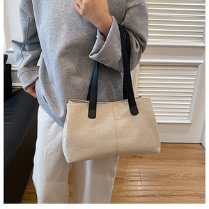 Dettaglio della borsa tote in tela con spalline in pelle nera indossata da modella