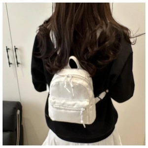 Close-up of white corduroy mini backpack showing textured fabric and zipper pocket