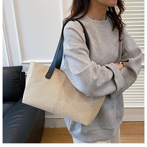 Grande borsa tote in tela con tracolle nere indossata a spalla in un ambiente domestico