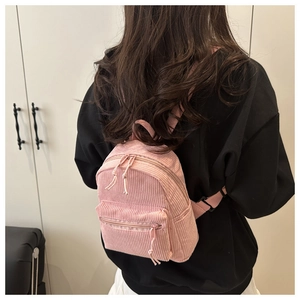 Pink corduroy mini backpack on back with zip pocket and visible ribbed texture