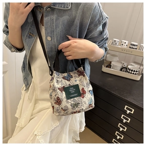 Floral canvas bag with butterfly print and green label worn by a model in casual style