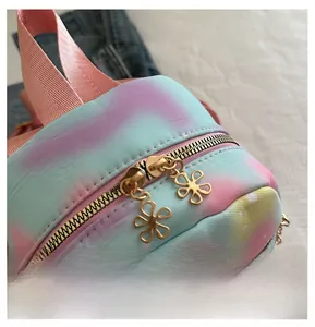 Detailed macro view of smooth golden flower-shaped zippers on a tie-dye pastel backpack