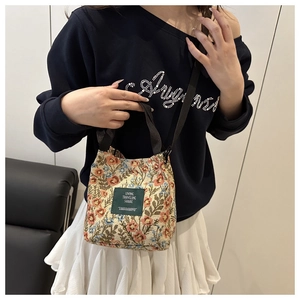 Détail d'un sac à main en toile fleurie avec étiquette verte et bandoulière ajustable