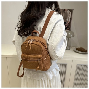 Nahaufnahme der braunen Cord-Struktur eines stylischen Mini-Rucksacks getragen von Model