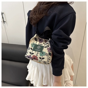 Detailed shot of vintage floral canvas tote bag featuring a green woven label and black handle