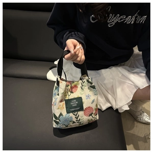 Detailed embroidery on canvas floral tote with black woven handle and central label