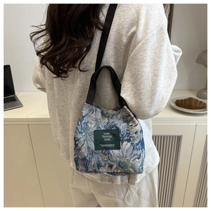 Photo lifestyle d'un sac en toile fleurie bleue avec bandoulière et poignée