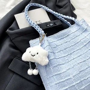 Dettaglio della borsa tote azzurra testurizzata con ciondolo a nuvola su blazer