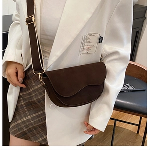 Detail der dunkelbraunen Satteltasche mit breitem Riemen und goldener Hardware am Modell