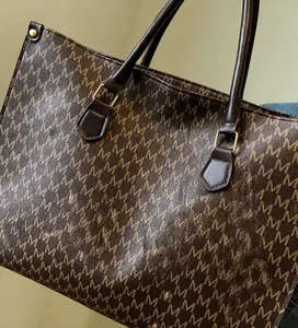 Detailed macro view of brown monogram print tote with leather straps and gold rivets