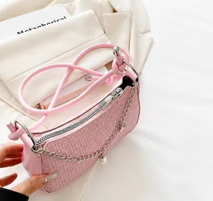 Detailed macro view of pink woven texture bag with silver zipper and pearl chain pendant