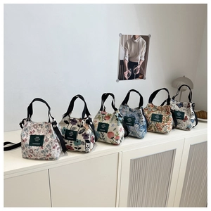 Groupe de six sacs en toile à fleurs avec anses noires sur une étagère minimaliste