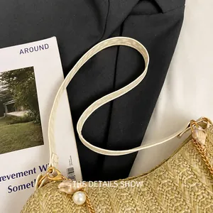 Detail van stro geweven tas met wit lederen handvat en een schelpparel hanger versiering
