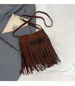 Detail shot of brown faux suede crossbody bag with long fringe tassels and thin strap