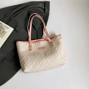 Top view of cream quilted tote bag with pink leather handles and fashion magazine