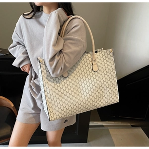 Detail of vintage beige tote bag with M-pattern print and reinforced shoulder strap rivets