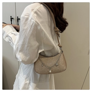 Détail du sac sous l'aisselle à paillettes champagne avec perles et breloques cœur
