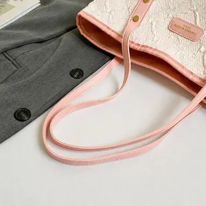 Detail shot of the white quilted texture and pink leather handle of this tote bag