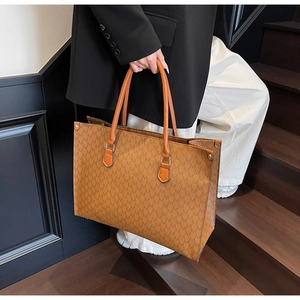 Detail of vintage brown monogram tote bag with double handles in a modern staircase setting