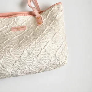 Detail showing the quilted fabric texture and pink leather handle with gold rivets