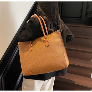 Brown monogram tote bag with classic M pattern and golden hardware shown on shoulder