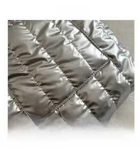 Detail of silver quilted tote bag fabric with metallic gloss and square stitching