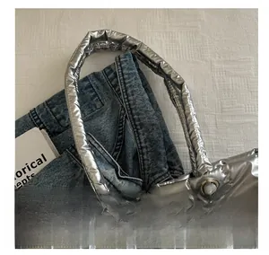 Macro detail of silver quilted tote bag showing thick padded handles and metallic finish
