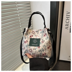 Floral canvas handbag with green label and black adjustable strap in cream white