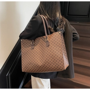 Close-up of vintage brown tote bag featuring repeated M pattern and leather handles