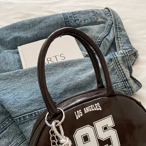 Detailed close-up of dark brown patent leather tote bag with Los Angeles print on denim