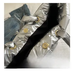 Detail shot of the silver quilted tote bag showing secure golden magnetic snap closures