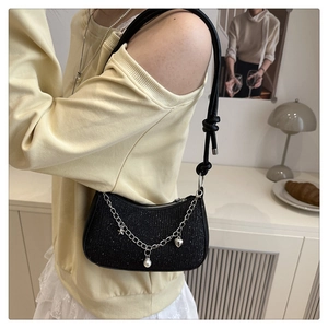 Detail of black sequined underarm bag with silver chain, pearl and heart charms