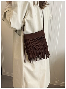 Close-up of retro brown fringe crossbody bag paired with a stylish beige trench coat