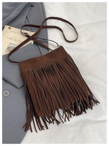 Gros plan détaillé du sac seau en daim marron avec de longues franges et lanière