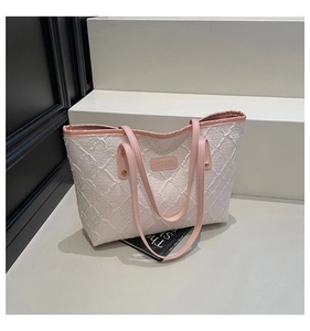 Detailed close-up of quilted jacquard fabric and pink leather straps on large tote bag