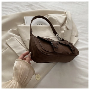 Detail view of coffee suede shoulder bag with dual buckled pockets on a blazer