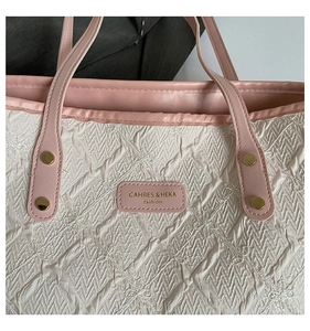 Close-up of beige quilted fabric texture with pink leather trim and gold metal rivets