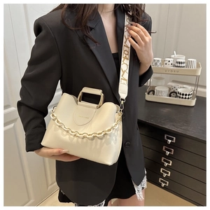 Chic beige bucket bag with metal handle and geometric wide strap on a black blazer