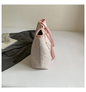 Close-up of white floral embroidery detail and pink PU handle on tote bag