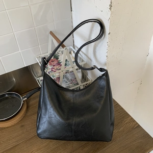 Minimalist black faux leather tote bag with vintage texture and sleek shoulder strap